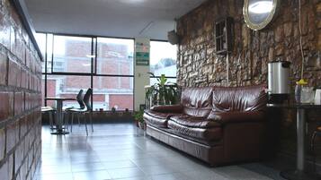 Un hall con un sofá de cuero, una cafetera y una pared de piedra.
