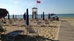 A beach with sun loungers, umbrellas, and a lifeguard tower. - Hotel San Marco (San Michele al Tagliamento)