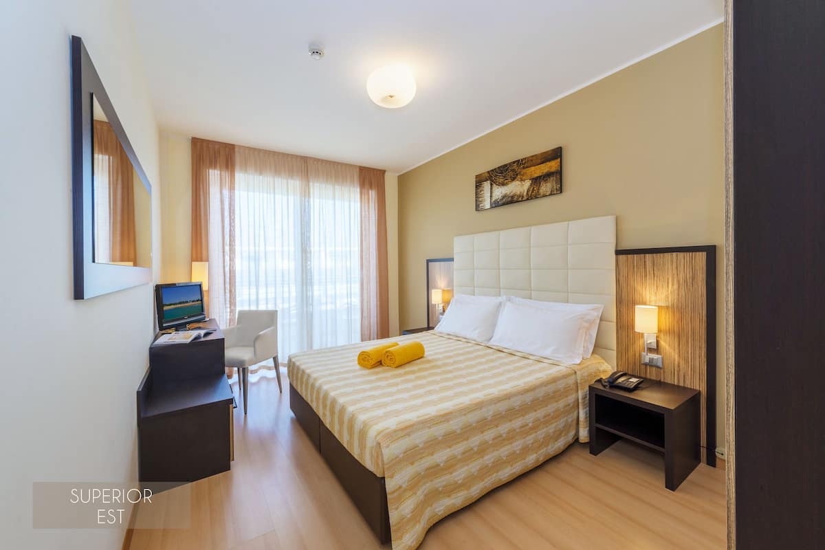 Een hotelkamer met een bed, bureau, stoel en bedlampjes.