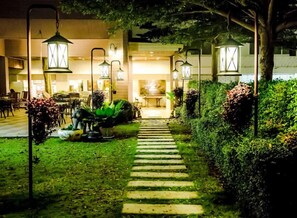 Un camino bien iluminado al aire libre que lleva a un edificio con zona de comedor.