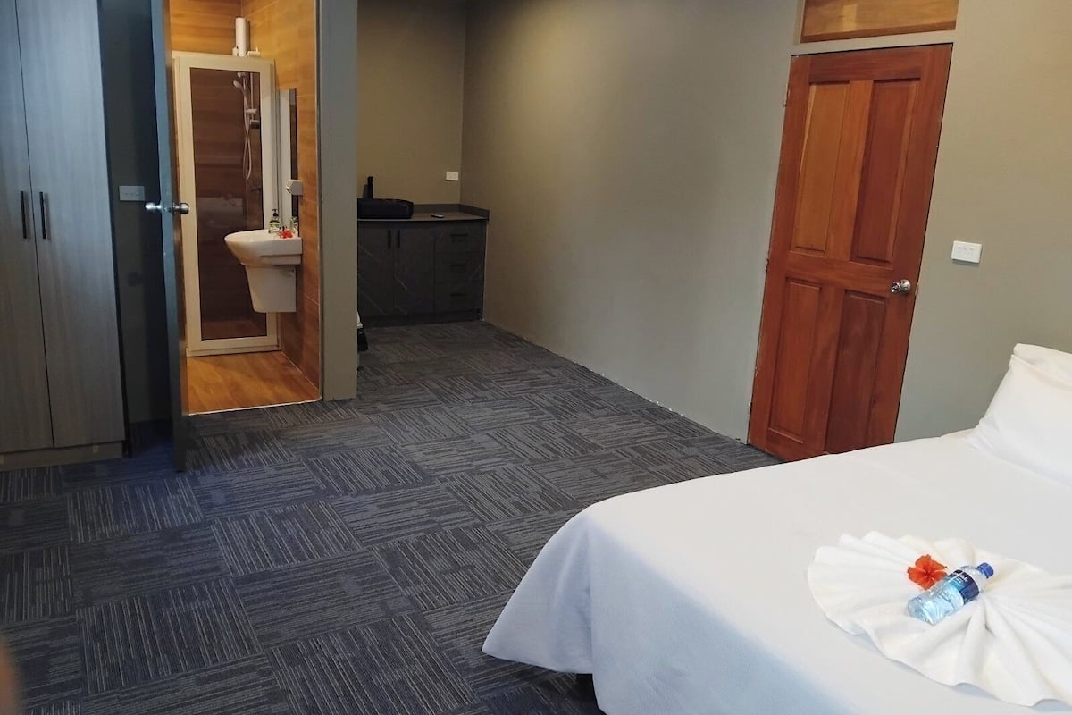 A hotel room with a bed, a wardrobe, a bathroom with a toilet, and a sink.