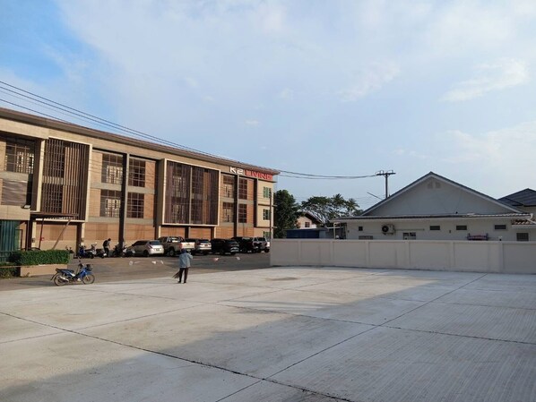Un amplio estacionamiento de concreto con un edificio identificado como "K2 LIVING" al fondo.