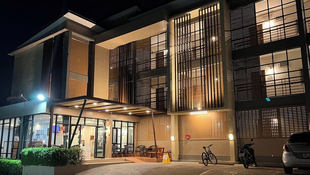 Un edificio de varios pisos con amplios ventanales y un área de entrada cubierta.