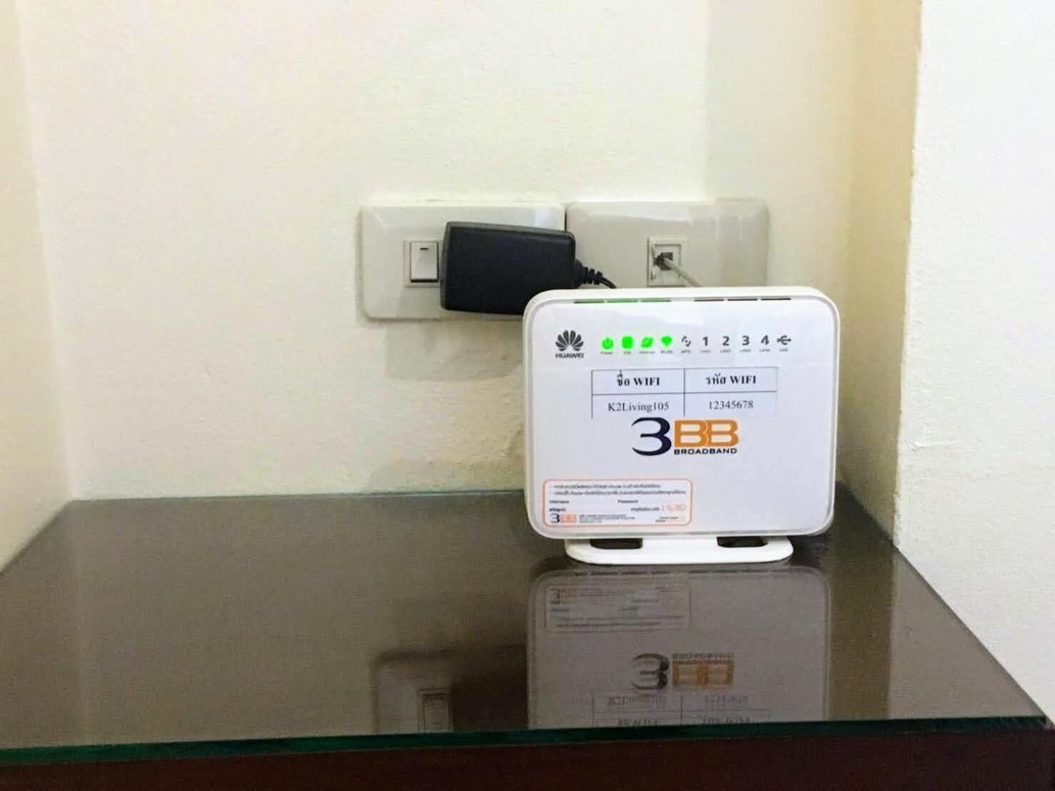 Un router de banda ancha Huawei 3BB sobre una mesa de vidrio frente a una pared blanca.