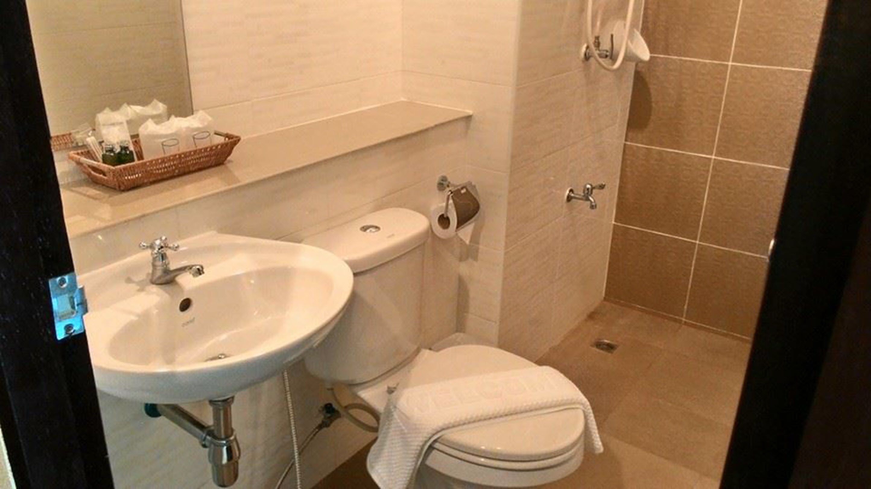 Et badeværelse med hvid vask, toilet og bruseniche.