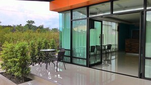 Un edificio moderno con grandes puertas de vidrio que dan a un patio al aire libre con dos mesas y sillas.
