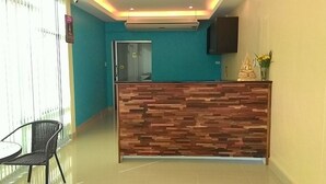 Un área de recepción con un mostrador de madera, una silla y un televisor montado en la pared.