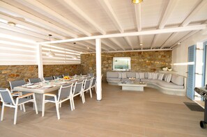 Un espace intérieur spacieux comprenant une table à manger pour six personnes, un canapé et un mur en pierre.