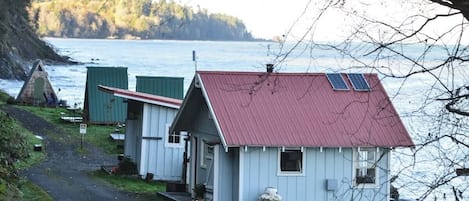 A row of small, single-story cabins with red roofs, situated by a body of water.