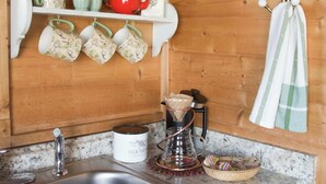 Uma cozinha com cafeteira, chaleira e bule sobre o balcão.