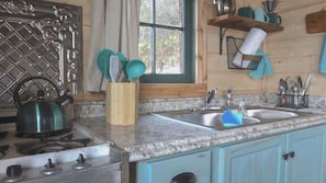 Una cucina con piani di lavoro in granito, un fornello, due lavandini e pensili in legno.