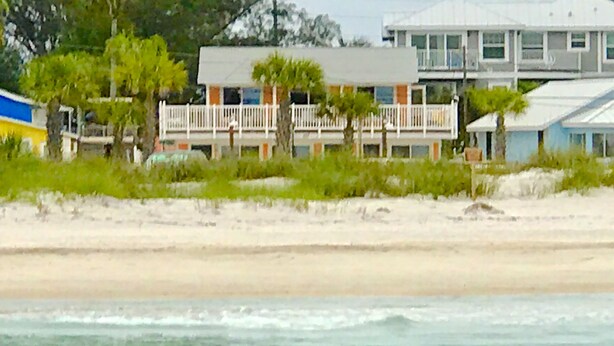 Un hotel frente a la playa con edificios de varios pisos, una playa arenosa y vista al océano.