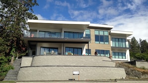 Un bâtiment moderne à plusieurs étages, doté de grandes fenêtres, d’un toit plat et d’un mur de soutènement en pierre.