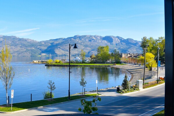 A lakeside view with a road, lamp posts, and a distant mountain range.