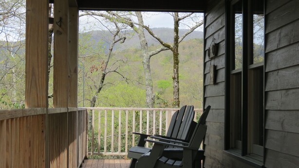 A wooden deck with a chair and a window overlooking a forested area. - Mountain VIEW! -  Private-Romantic -Secluded -WiFi (Ellijay)