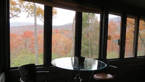 A room with a round glass table and two chairs, large windows with a view of autumn foliage. - Mountain VIEW! -  Private-Romantic -Secluded -WiFi (Ellijay)