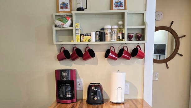 A kitchen with a wooden countertop, a coffee maker, a toaster, and a cutting board.