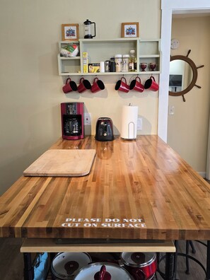 A kitchen with a wooden countertop, a coffee maker, a toaster, and a cutting board.