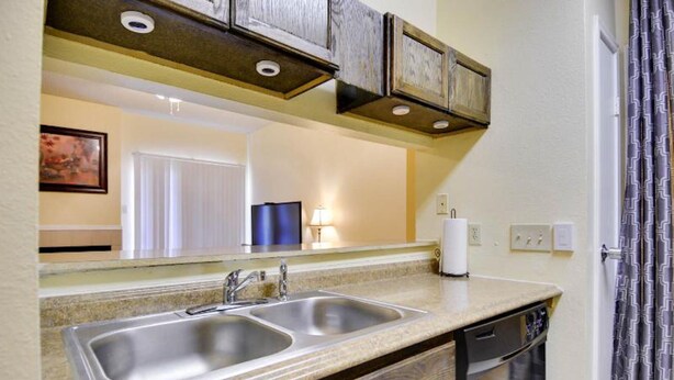 A kitchen with two stainless steel sinks, wooden cabinets, a built-in dishwasher, and a mirror above the counter. - Beautiful Condo Near The Domain (Austin)