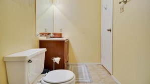A small bathroom with a toilet, sink, and mirror. - Beautiful Condo Near The Domain (Austin)
