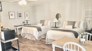 Hotellihuone, jossa on kaksi sänkyä, ruokapöytä, kattotuuletin ja televisio.