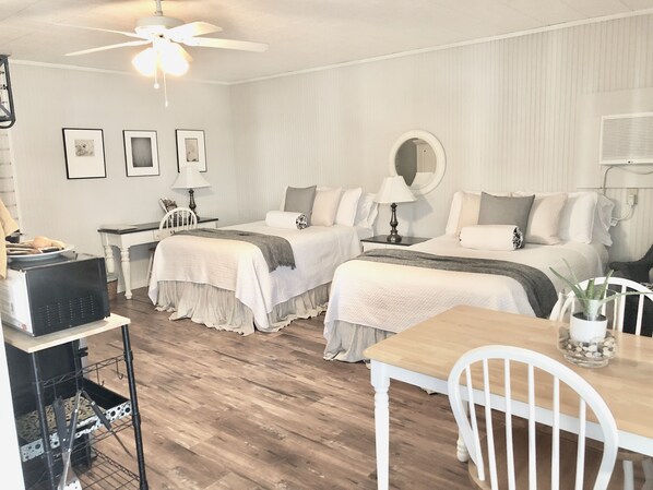 A hotel room with two beds, a dining table, a ceiling fan, and a TV. - Cottage with pool in historic downtown (Smithville)