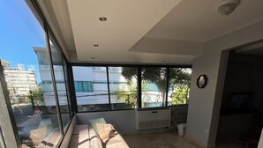 Una sala de estar moderna con un amplio ventanal, un sofá color beige y piso de baldosas.