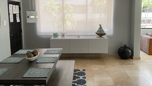 Una cocina moderna con un ventanal grande, una mesa de comedor con individuales y un banco empotrado con adornos.