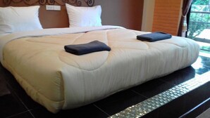 Een hotelkamer met een groot bed, een hoofdbord met een decoratief ontwerp en een raam met uitzicht op groen.