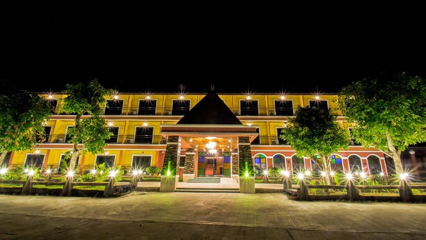 Een hotel met meerdere verdiepingen, een centrale ingang, diverse balkons en een goed verlichte gevel.
