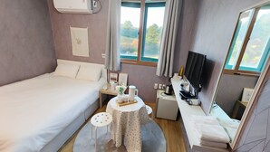A bedroom with a bed, bedside table, TV, and a window with curtains. - Gunsan La Siesta Hotel (Gunsan)