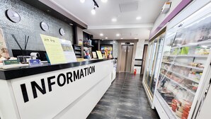 A reception area with a white counter labeled "INFORMATION," a clock, and a refrigerator stocked with beverages. - Gunsan La Siesta Hotel (Gunsan)