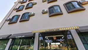 A building with multiple balconies and air conditioning units. The ground floor has a café named "La siesta café" with large windows and outdoor seating. - Gunsan La Siesta Hotel (Gunsan)