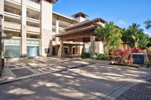 A multi-story hotel with a covered entrance, outdoor seating, and landscaped gardens.