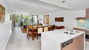 Une cuisine moderne dotée d’un îlot central, d’un coin repas avec des chaises en bois et d’une vue sur un balcon.