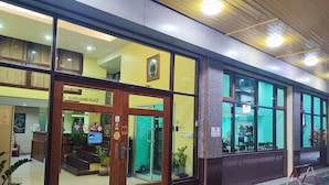 Entrada de hotel com porta de madeira e grandes janelas.