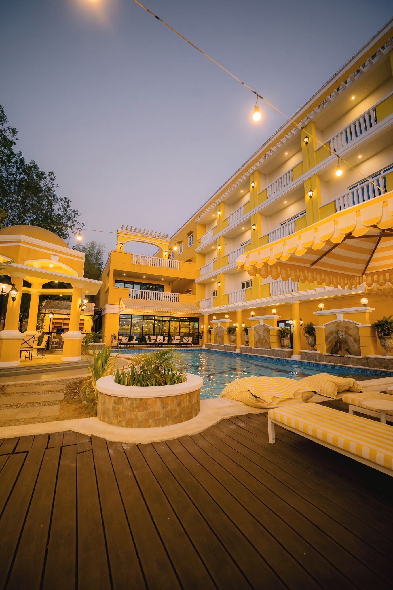 Un hôtel à plusieurs étages doté d’une piscine, d’un espace extérieur aménagé et d’une terrasse couverte.