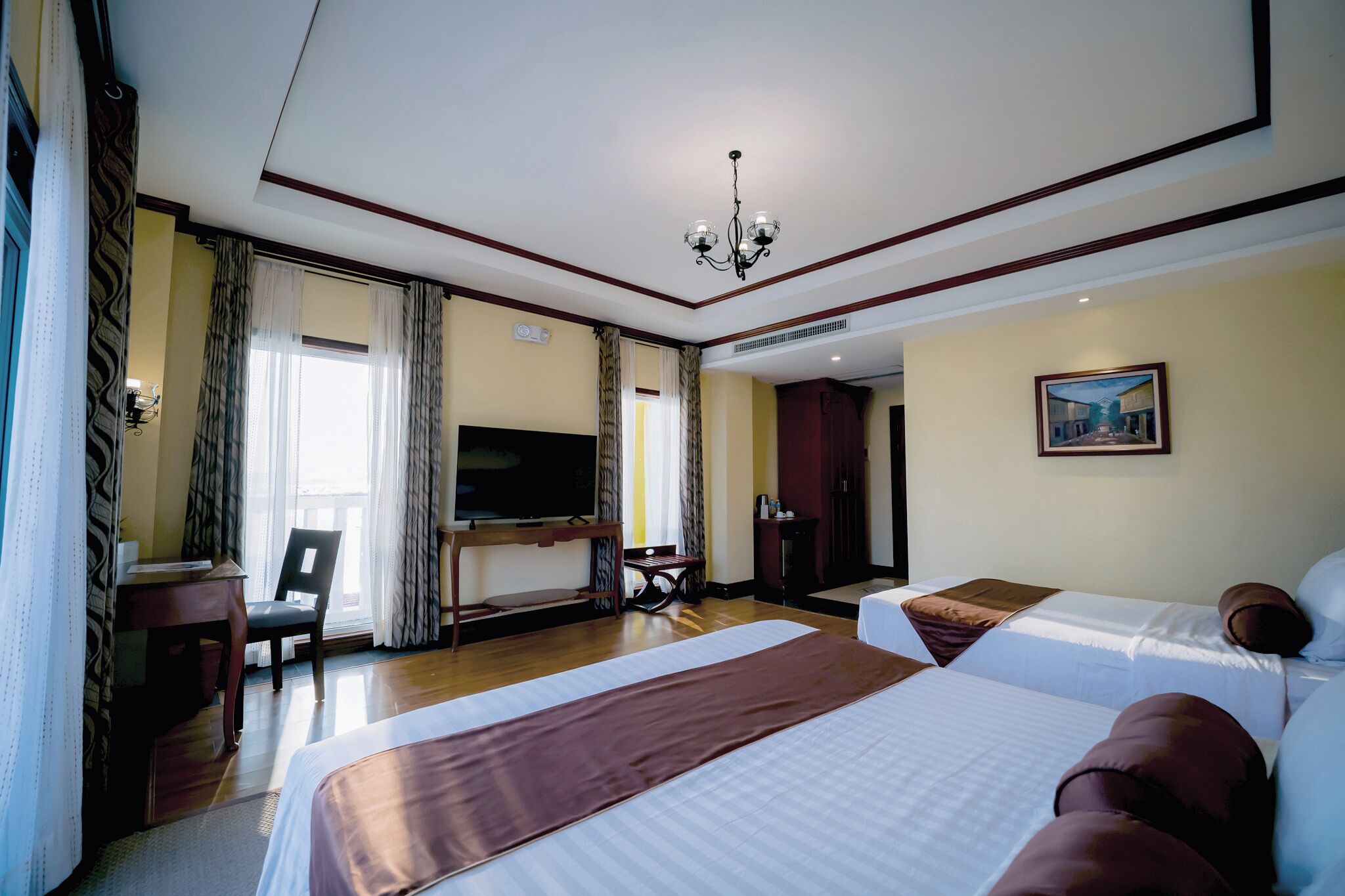 A hotel room with two beds, a TV, a desk, and a chair.