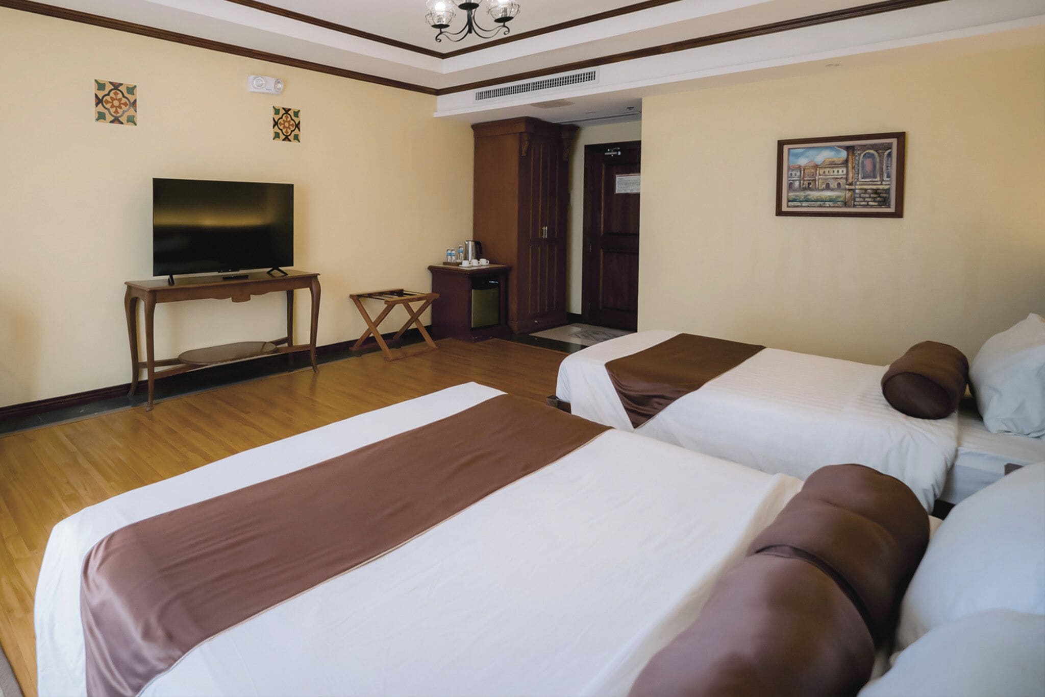 Een hotelkamer met twee bedden, een televisie, een tafeltje en een kast.