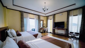 Habitación de hotel con dos camas, televisión, escritorio y una silla.