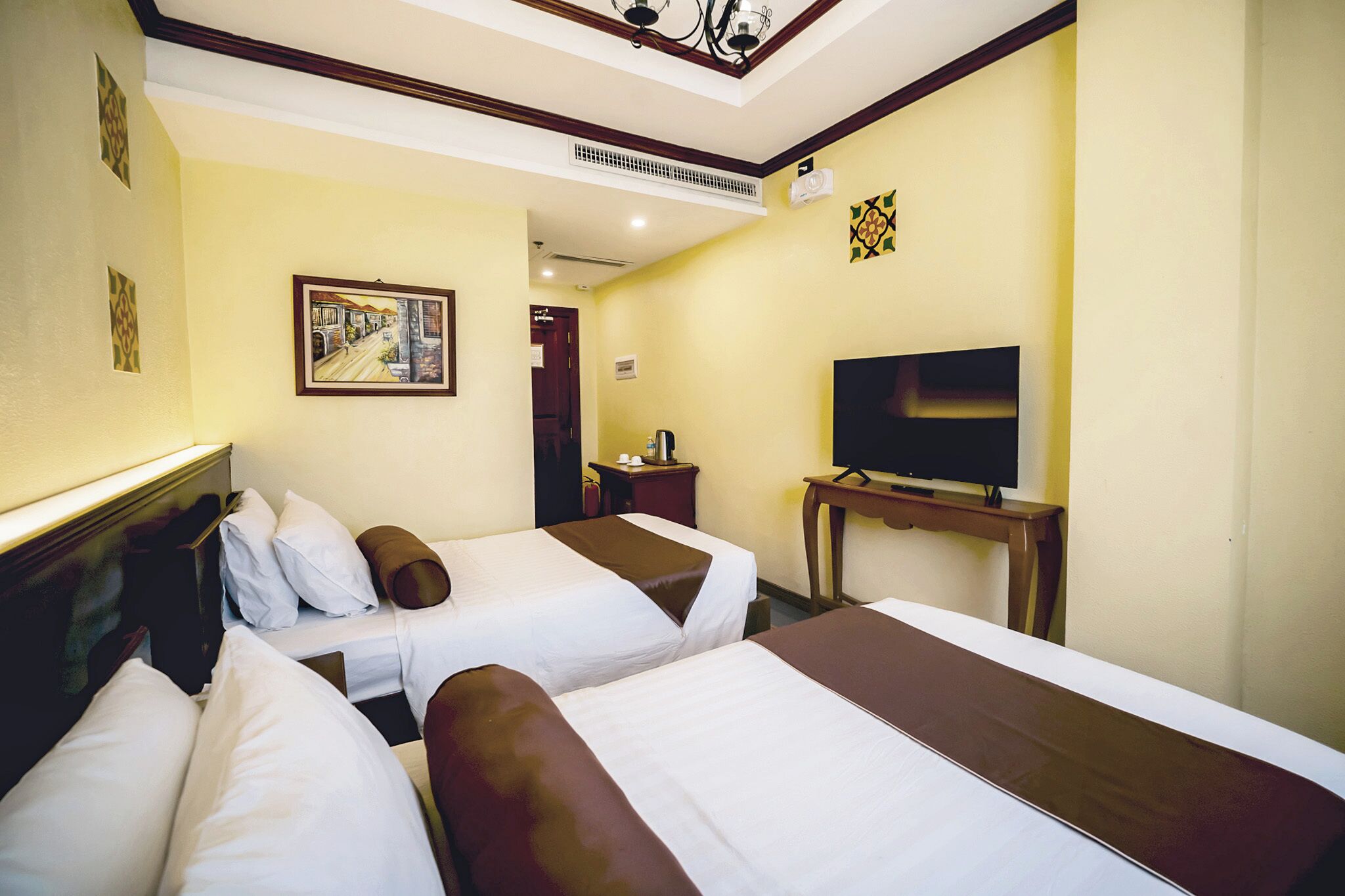Ein Hotelzimmer mit zwei Betten, einem Fernseher, einem Schreibtisch und einem Bild an der Wand.