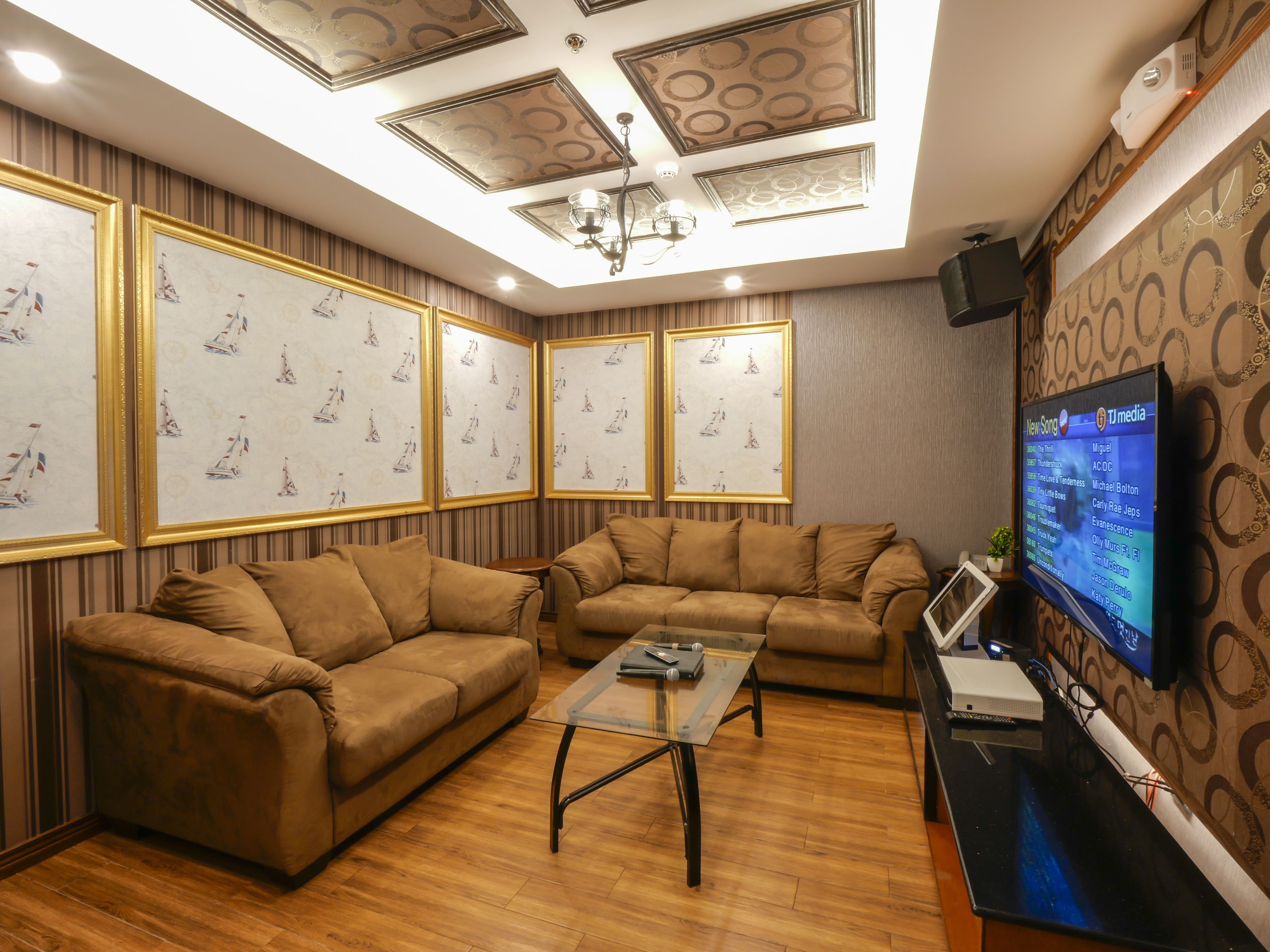 A living room with two brown sofas, a glass coffee table, and a flat-screen TV on a stand.