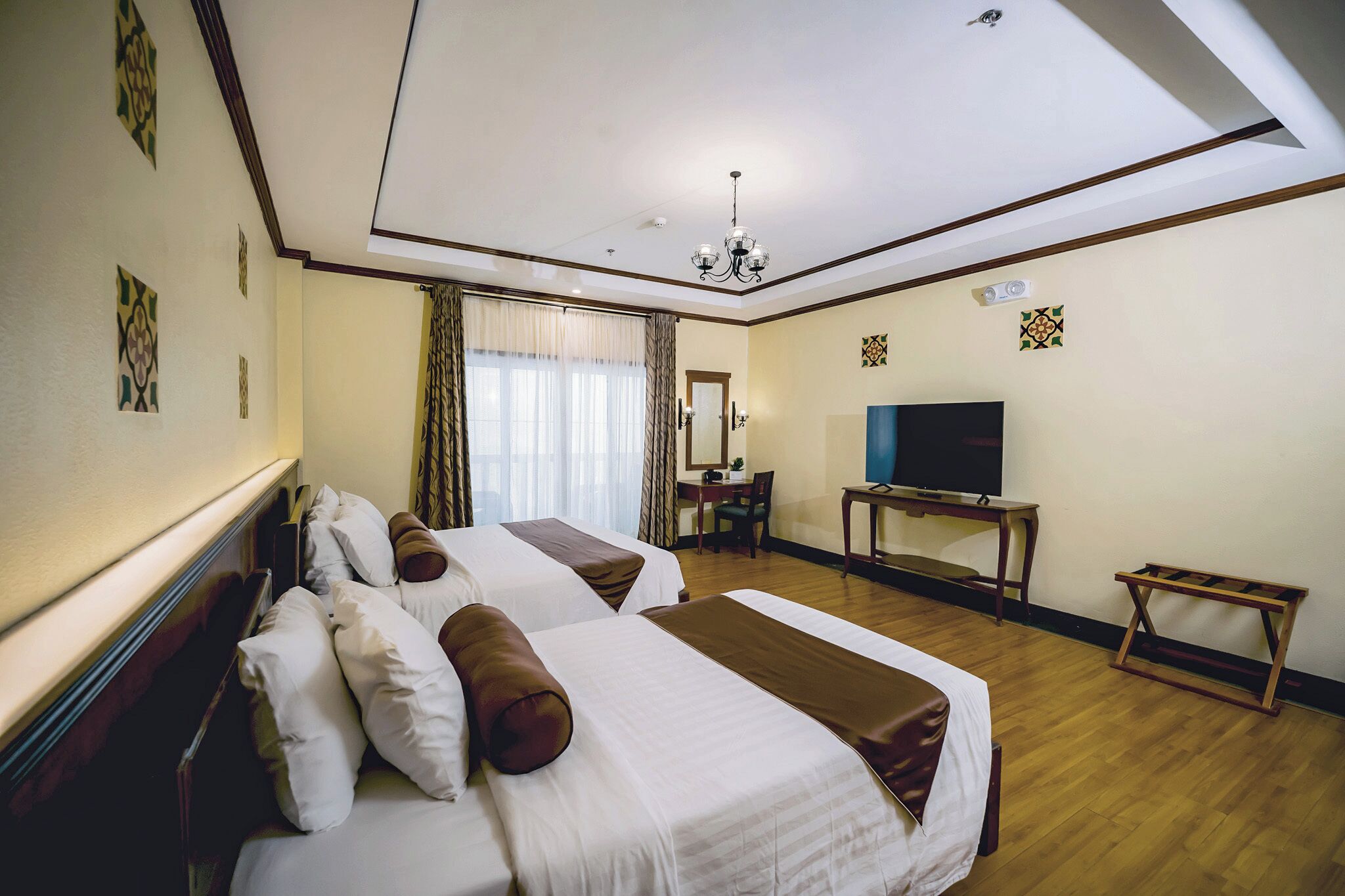 Habitación de hotel con dos camas, televisión, escritorio y una silla.