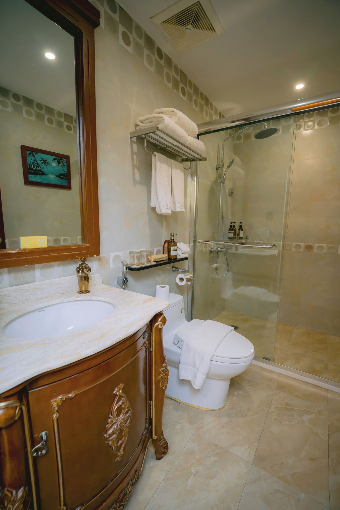 Un baño con lavamanos de mármol, inodoro, cabina de ducha de vidrio y espejo con marco decorativo.