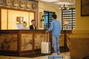 A reception desk with a marble front, clocks, and a chandelier.