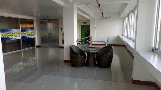 A clean, modern interior with a glass coffee shop sign, a staircase, and a seating area with wicker chairs. - Asia Novo Boutique Hotel - Sorsogon (Sorsogon City)