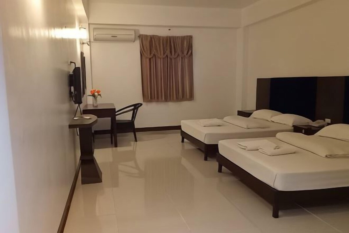 A hotel room with two beds, a desk with a chair, a TV, and a window with curtains.