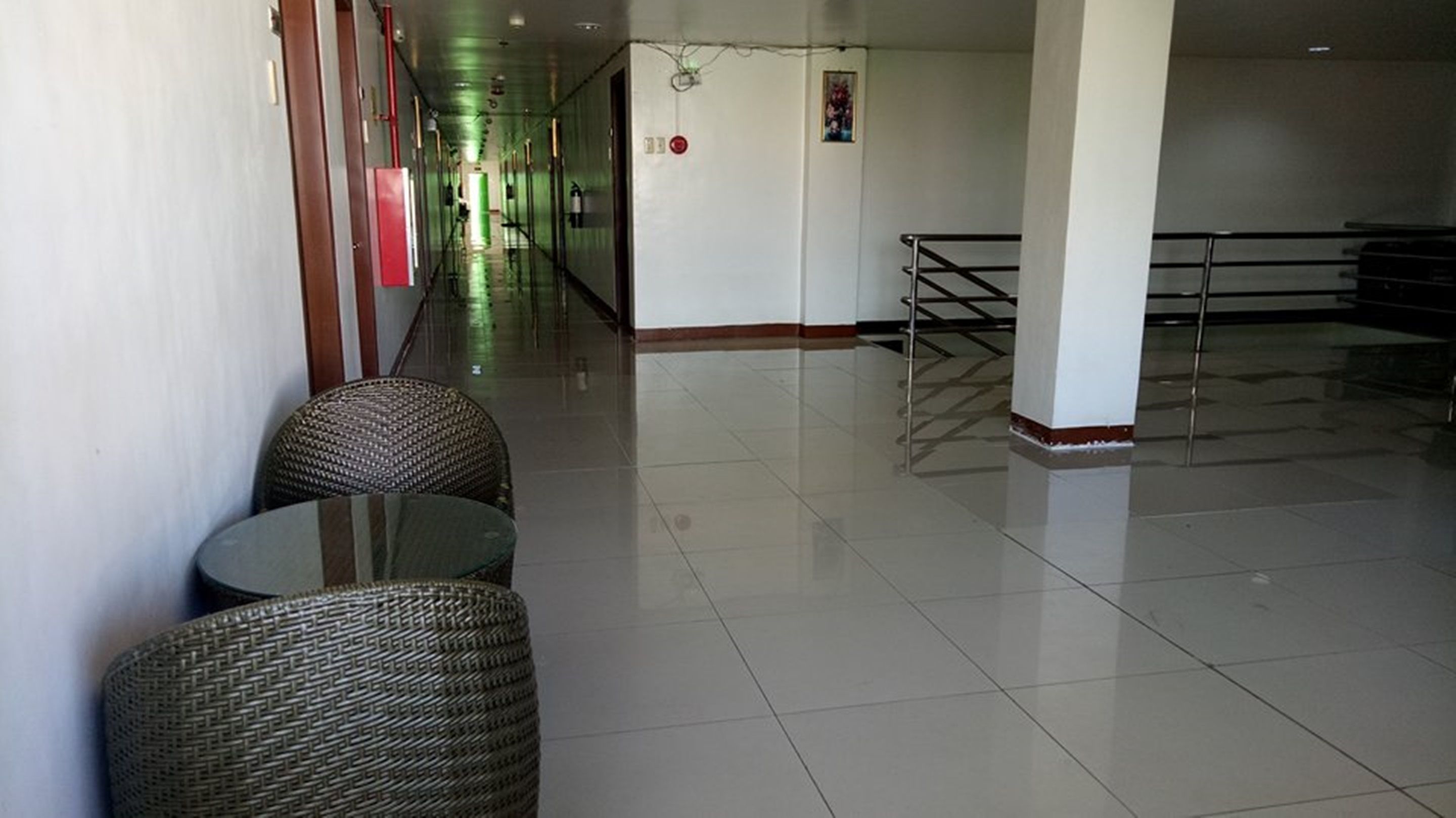 A spacious lobby with a tiled floor, a staircase, and wicker chairs.