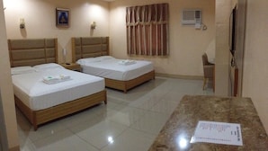 Quarto de hotel com duas camas de solteiro, uma mesa de mármore, uma cadeira, televisão, ar condicionado e um quadro na parede.