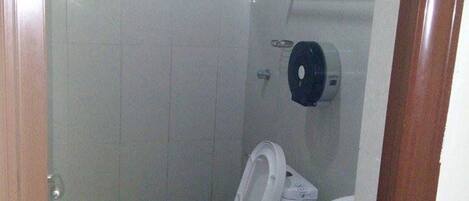 Un baño pequeño y funcional con inodoro, lavamanos y dispensador de papel higiénico.